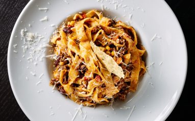 A tasty fettuccine pasta dish topped with grated cheese on a white plate